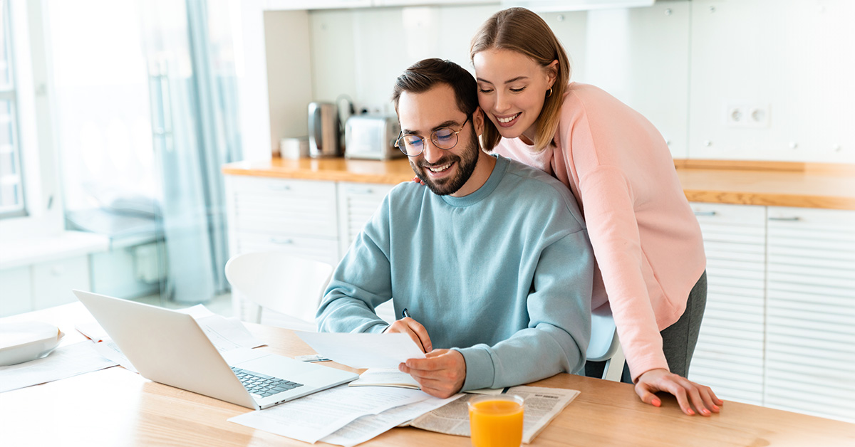 Portrait of young smiling couple working with laptop